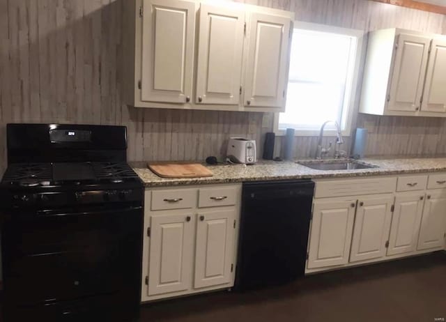 kitchen featuring decorative backsplash, white cabinetry, a sink, light stone countertops, and black appliances