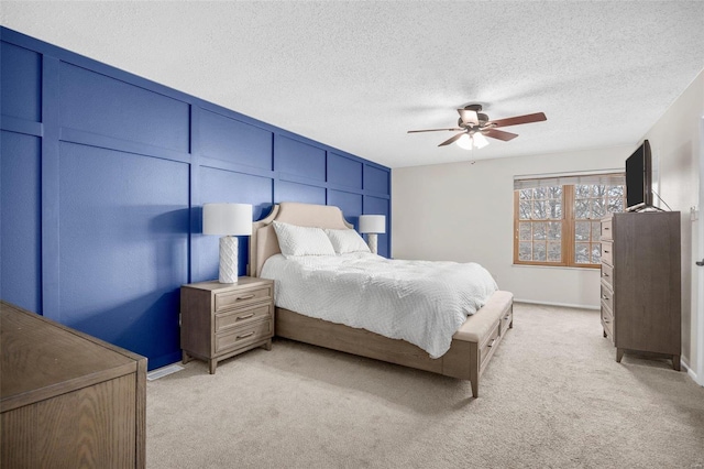 bedroom featuring a textured ceiling, baseboards, a ceiling fan, and light colored carpet