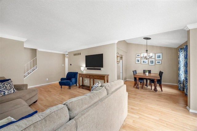 living area with visible vents, light wood-style flooring, stairs, vaulted ceiling, and a chandelier