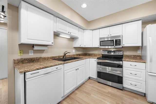 kitchen featuring stainless steel appliances, light wood-style floors, a sink, and white cabinets