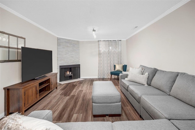 living room with crown molding, baseboards, wood finished floors, and a stone fireplace