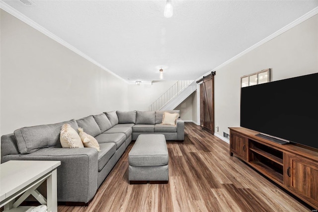 living area with stairway, a barn door, ornamental molding, a textured ceiling, and wood finished floors