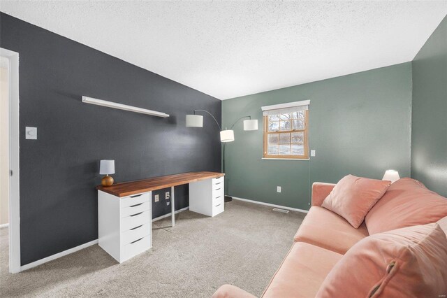 office with baseboards, a textured ceiling, and light colored carpet