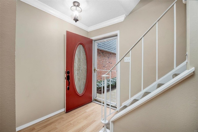 foyer entrance with baseboards, ornamental molding, stairs, a textured ceiling, and light wood-type flooring