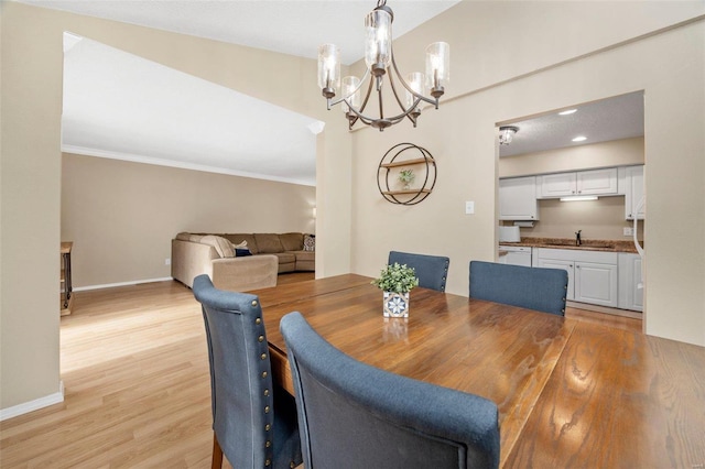 dining space with light wood-type flooring, crown molding, baseboards, and an inviting chandelier