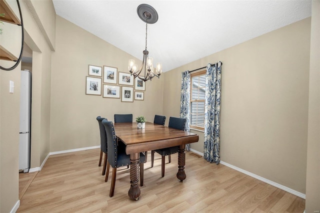 dining space with light wood-type flooring, baseboards, and vaulted ceiling