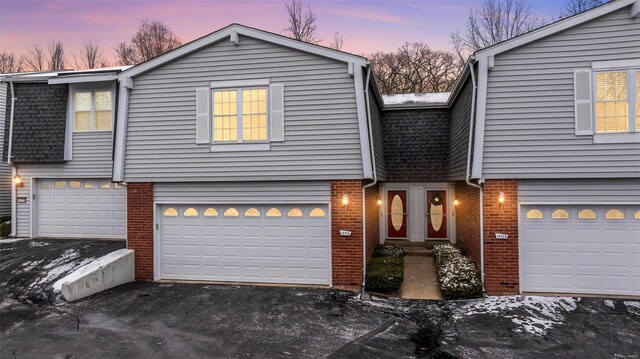 view of front of house featuring aphalt driveway, brick siding, an attached garage, and roof with shingles