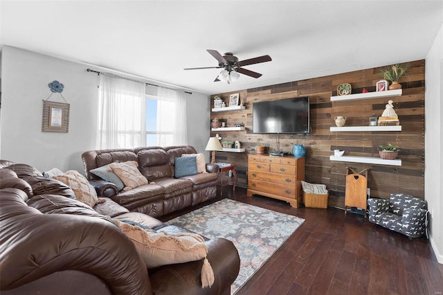 living area featuring ceiling fan, wood walls, and dark wood-style flooring