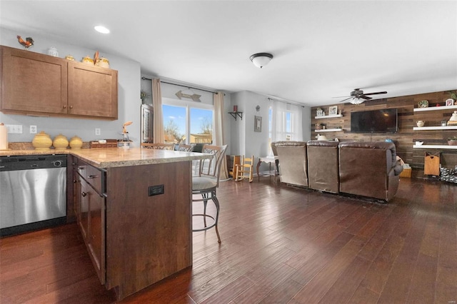 kitchen featuring dark wood-style floors, light stone counters, open floor plan, a kitchen bar, and stainless steel dishwasher