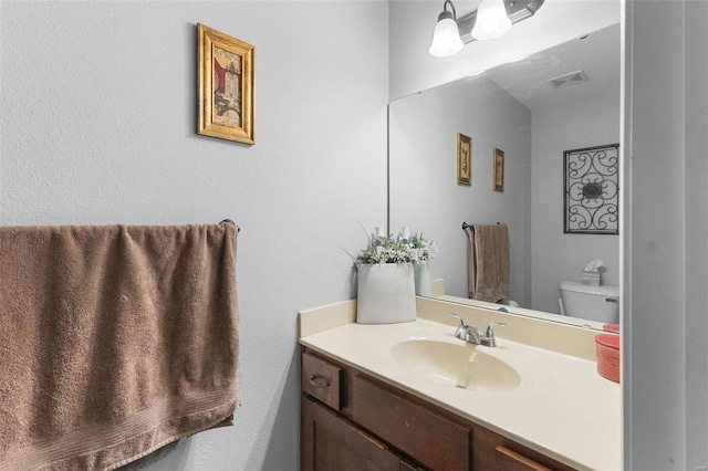 bathroom with toilet, visible vents, and vanity