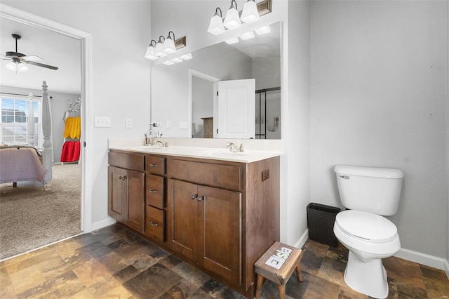 ensuite bathroom with double vanity, baseboards, toilet, stone finish floor, and a sink