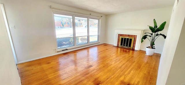 unfurnished living room featuring a fireplace, light wood-style flooring, and baseboards