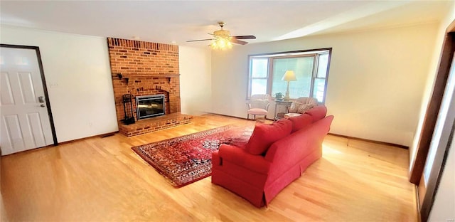 living room featuring a brick fireplace, light wood-style flooring, baseboards, and ceiling fan