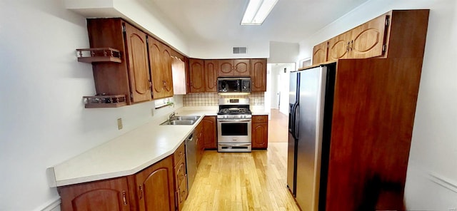 kitchen featuring refrigerator with ice dispenser, light countertops, light wood-type flooring, decorative backsplash, and gas range