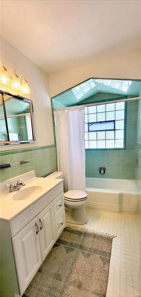 full bath with a wainscoted wall, tile walls, toilet, shower / bath combo, and vanity