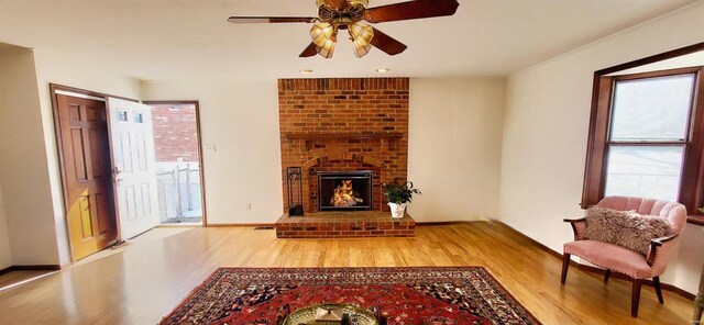 living area with a fireplace, wood finished floors, a ceiling fan, and baseboards