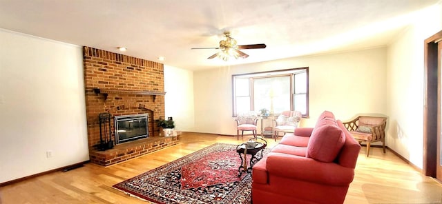 living room with a ceiling fan, a fireplace, baseboards, and wood finished floors