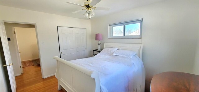 bedroom with light wood-type flooring, baseboards, a ceiling fan, and a closet