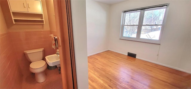 bathroom with toilet, a sink, visible vents, wood finished floors, and baseboards