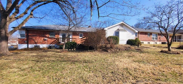 rear view of property with brick siding and a lawn