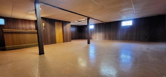 basement with wooden walls, a drop ceiling, and tile patterned floors