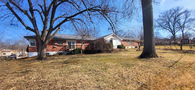 back of house with brick siding, a deck, and a yard