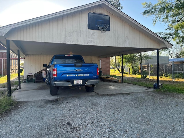 view of vehicle parking featuring a carport, gravel driveway, and fence