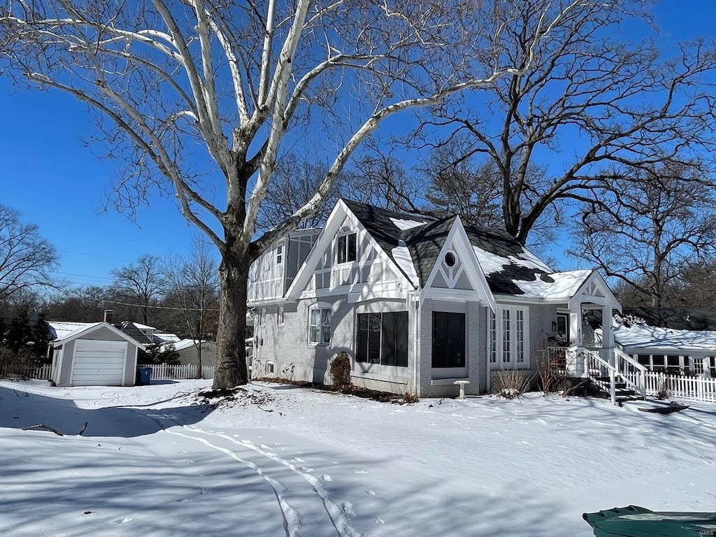 view of front of home featuring brick siding, a detached garage, and fence