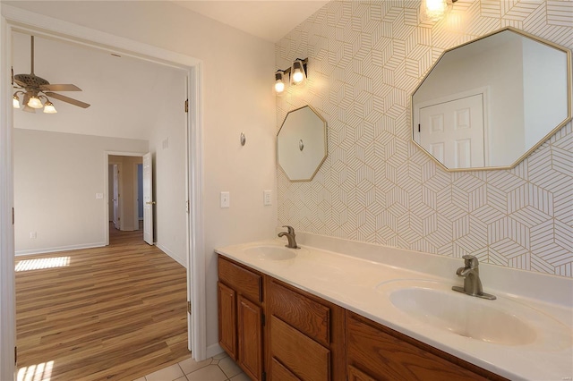 full bathroom with double vanity, ceiling fan, a sink, and wood finished floors