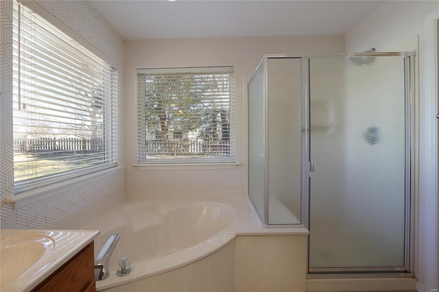 bathroom featuring a stall shower, a garden tub, vanity, and a healthy amount of sunlight