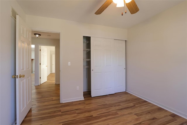 unfurnished bedroom featuring visible vents, baseboards, a ceiling fan, wood finished floors, and a closet