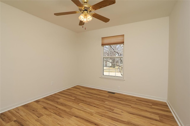 spare room featuring ceiling fan, light wood finished floors, visible vents, and baseboards