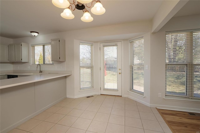 kitchen featuring baseboards, visible vents, light countertops, a chandelier, and a sink