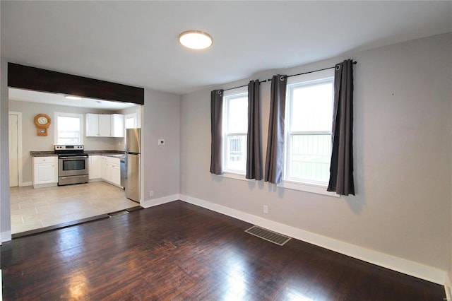 unfurnished living room featuring light wood-style flooring, visible vents, and baseboards