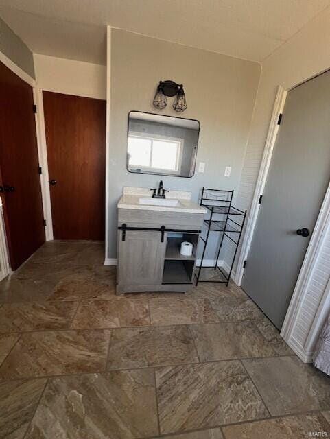 bathroom with stone finish flooring, vanity, and baseboards