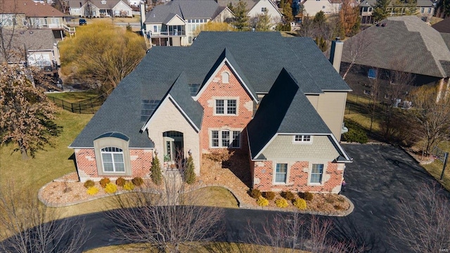 view of front of property featuring a shingled roof, a residential view, and brick siding