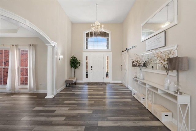 foyer entrance with baseboards, a high ceiling, wood finished floors, and a notable chandelier