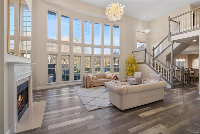 living area with baseboards, wood finished floors, stairs, a fireplace, and a notable chandelier