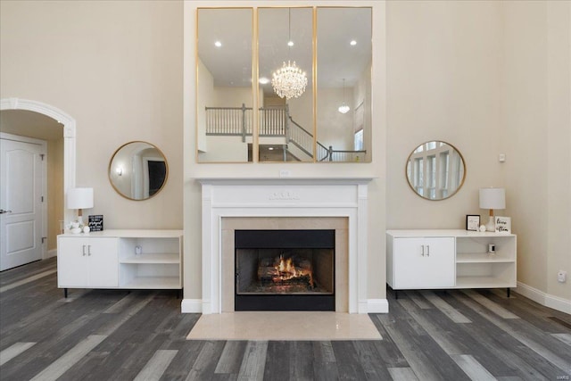 unfurnished living room featuring baseboards, a high ceiling, wood finished floors, and an inviting chandelier