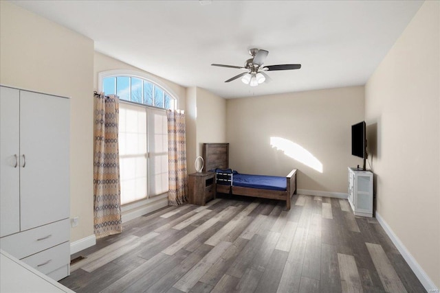 bedroom with a ceiling fan, wood finished floors, visible vents, and baseboards