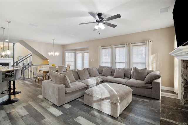 living room with dark wood-style floors, a fireplace, and ceiling fan with notable chandelier