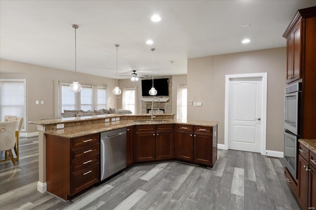 kitchen with ceiling fan, open floor plan, wood finished floors, stainless steel appliances, and a sink