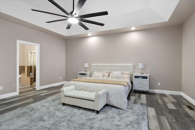 bedroom featuring a tray ceiling, dark wood-style flooring, visible vents, and baseboards