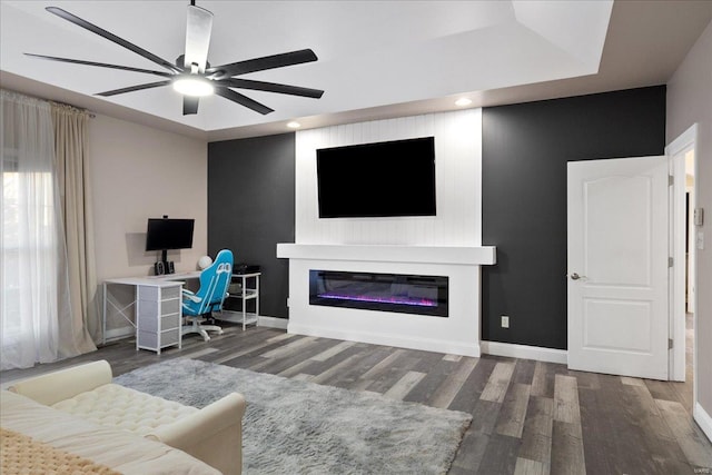 living room featuring a glass covered fireplace, baseboards, and wood finished floors