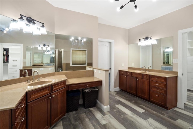 bathroom featuring baseboards, two vanities, a sink, and wood finished floors