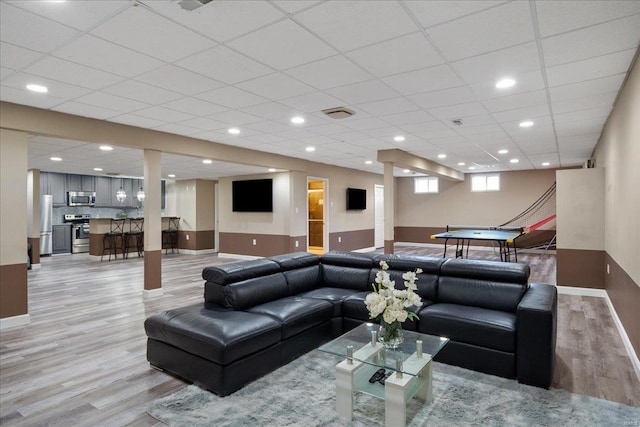 living area with a paneled ceiling, light wood finished floors, and baseboards