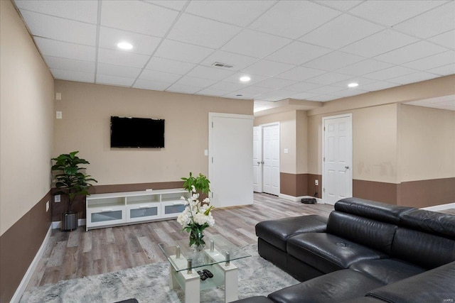 living area with a drop ceiling, recessed lighting, wood finished floors, visible vents, and baseboards