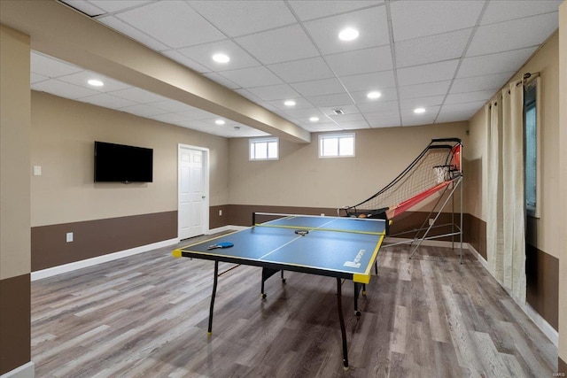 recreation room featuring a paneled ceiling, baseboards, wood finished floors, and recessed lighting