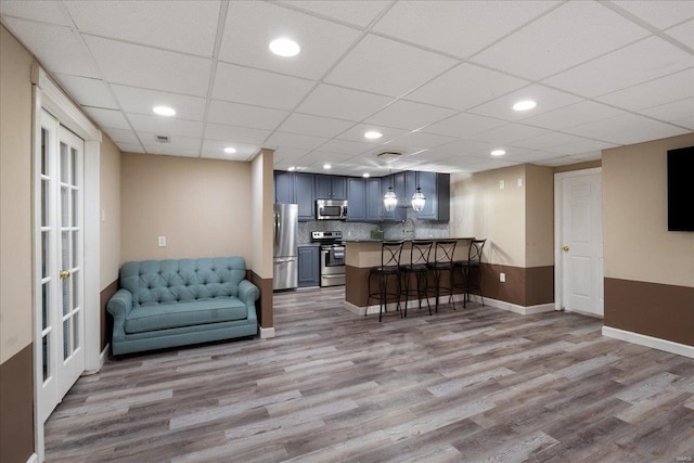 interior space featuring recessed lighting, a drop ceiling, baseboards, and wood finished floors