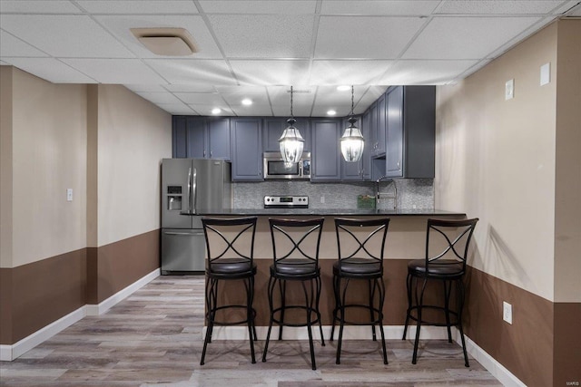 kitchen featuring a peninsula, dark countertops, light wood-type flooring, and stainless steel appliances